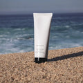 White tube of Mint Exfoliating Facial Polish on sand showcasing skincare luxury